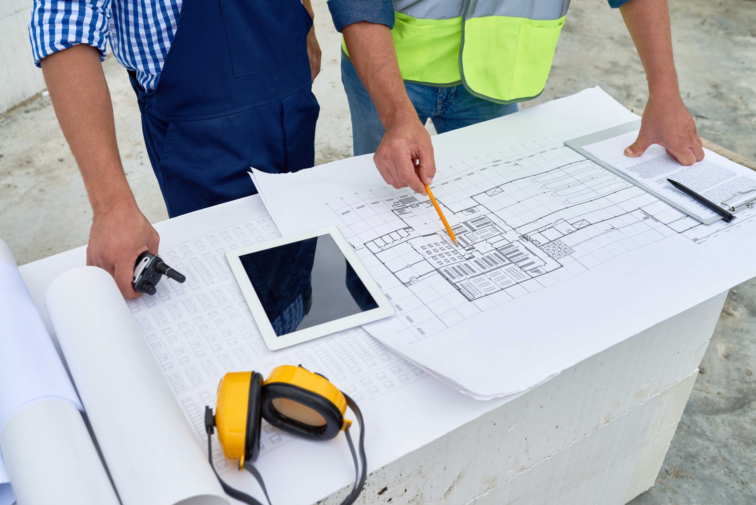Construction professionals reviewing engineering floor plans and drawings on site